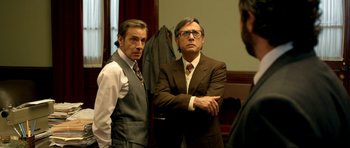 Movie still from “The Secret in Their Eyes” (2009), directed by Juan José Campanella – Two men standing next to each other in a room; Medium shot, Over the shoulder angle