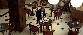 Movie still from “The Secret in Their Eyes” (2009), directed by Juan José Campanella – A man sitting at a table in a restaurant; Wide shot, High angle