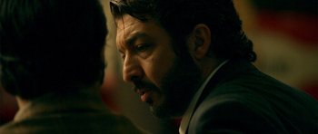 Movie still from “The Secret in Their Eyes” (2009), directed by Juan José Campanella – A person wearing a suit and beard; Close Up shot, Over the shoulder angle