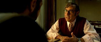 Movie still from “The Secret in Their Eyes” (2009), directed by Juan José Campanella – A man wearing glasses and a vest talking to another man; Close Up shot, Over the shoulder angle