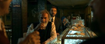 Movie still from “The Secret in Their Eyes” (2009), directed by Juan José Campanella – A group of people sitting at a table with drinks; Medium shot, Over the shoulder angle