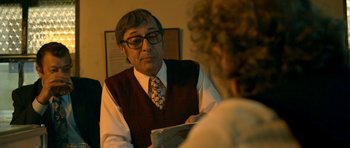 Movie still from “The Secret in Their Eyes” (2009), directed by Juan José Campanella – An older man wearing glasses and a vest is talking to an older woman; Close Up shot, Over the shoulder angle