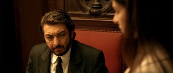 Movie still from “The Secret in Their Eyes” (2009), directed by Juan José Campanella – A man in a suit and tie sitting in front of another man; Close Up shot, Over the shoulder angle