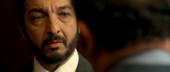 Movie still from “The Secret in Their Eyes” (2009), directed by Juan José Campanella – A person wearing a suit and beard; Extreme Close Up shot, Over the shoulder angle