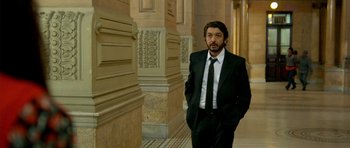 Movie still from “The Secret in Their Eyes” (2009), directed by Juan José Campanella – A man in a suit and tie standing in a hallway; Medium shot, Low angle