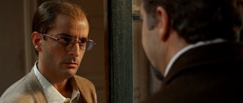 Movie still from “The Secret in Their Eyes” (2009), directed by Juan José Campanella – A man in a suit and glasses looking at another man in a suit and glasses; Close Up shot, Over the shoulder angle