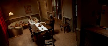Movie still from “The Secret in Their Eyes” (2009), directed by Juan José Campanella – Two people sitting at a table in a room; Wide shot, High angle
