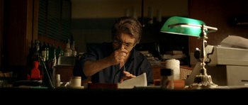 Movie still from “The Secret in Their Eyes” (2009), directed by Juan José Campanella – A man sitting at a desk writing on a piece of paper; Medium shot, Low angle