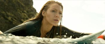 Movie still from “The Shallows” (2016), directed by Jaume Collet-Serra – A person sitting on a surfboard in the water; Close Up shot, Low angle