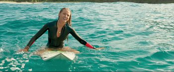 Movie still from “The Shallows” (2016), directed by Jaume Collet-Serra – A beautiful young woman riding a surfboard on top of water; Medium shot, High angle