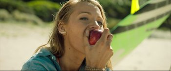 Movie still from “The Shallows” (2016), directed by Jaume Collet-Serra – A woman eating an apple outside in the sun; Close Up shot, Low angle