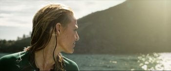 Movie still from “The Shallows” (2016), directed by Jaume Collet-Serra – A young woman with dreadlocks is listening to music while standing by the water; Close Up shot, Over the shoulder angle