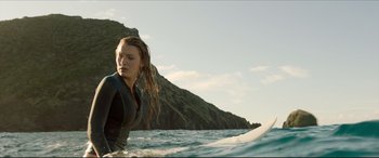 Movie still from “The Shallows” (2016), directed by Jaume Collet-Serra – A woman standing on a surfboard in the ocean; Medium shot, Low angle