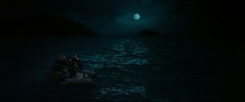 Movie still from “The Shallows” (2016), directed by Jaume Collet-Serra – A person sitting on a rock in the middle of the night; Extreme Wide shot, High angle