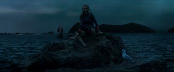 Movie still from “The Shallows” (2016), directed by Jaume Collet-Serra – A woman sitting on top of a rock on the beach; Wide shot, Low angle