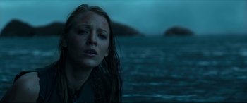Movie still from “The Shallows” (2016), directed by Jaume Collet-Serra – A woman with wet hair standing in front of a body of water; Close Up shot, Low angle