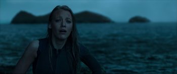Movie still from “The Shallows” (2016), directed by Jaume Collet-Serra – A woman standing on the beach at night looking sad; Medium shot, Low angle