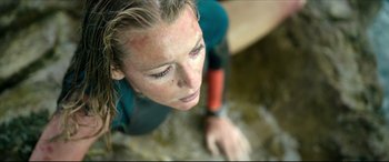 Movie still from “The Shallows” (2016), directed by Jaume Collet-Serra – A woman in a wetsuit looking down at the ground; Close Up shot, High angle