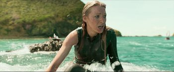 Movie still from “The Shallows” (2016), directed by Jaume Collet-Serra – A woman in a wetsuit riding a surfboard in the ocean; Medium shot, High angle