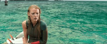 Movie still from “The Shallows” (2016), directed by Jaume Collet-Serra – A woman in a wetsuit standing in the water; Medium shot, High angle