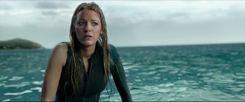 Movie still from “The Shallows” (2016), directed by Jaume Collet-Serra – A woman in a wet suit standing in front of a body of water; Medium shot, Low angle