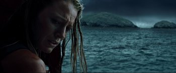 Movie still from “The Shallows” (2016), directed by Jaume Collet-Serra – A man with dreadlocks standing in front of a body of water; Close Up shot, Low angle