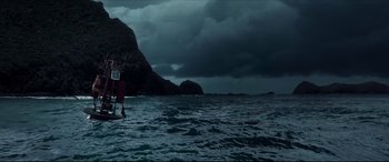 Movie still from “The Shallows” (2016), directed by Jaume Collet-Serra – A person on a surfboard in the ocean under a cloudy sky; Extreme Wide shot, Low angle