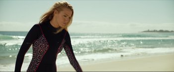 Movie still from “The Shallows” (2016), directed by Jaume Collet-Serra – A woman in a black wetsuit standing on a beach; Medium shot, Low angle