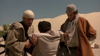 Movie still from “The Siege” (1998), directed by Edward Zwick – A group of men standing next to each other in the desert; Medium shot, Over the shoulder angle