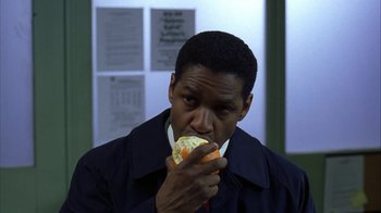 Movie still from “The Siege” (1998), directed by Edward Zwick – A man eating a hot dog on a bun; Close Up shot, High angle