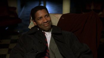 Movie still from “The Siege” (1998), directed by Edward Zwick – A man sitting in a chair wearing a jacket and a tie; Close Up shot, Over the shoulder angle