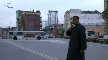 Movie still from “The Siege” (1998), directed by Edward Zwick – A man is standing on the side of the road talking on a phone; Wide shot, Low angle
