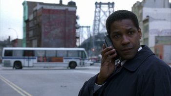Movie still from “The Siege” (1998), directed by Edward Zwick – A man talking on a cell phone while standing on the side of the road; Close Up shot, Low angle