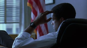Movie still from “The Siege” (1998), directed by Edward Zwick – A man sitting in front of an american flag; Close Up shot, Low angle