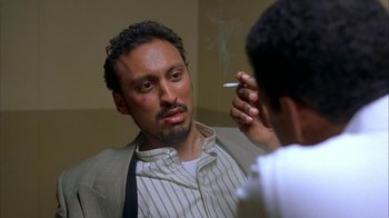 Movie still from “The Siege” (1998), directed by Edward Zwick – A man is looking at himself in the mirror while smoking a cigarette; Close Up shot, Low angle