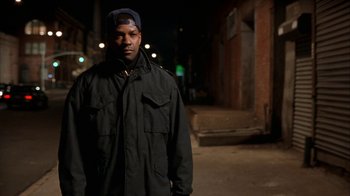 Movie still from “The Siege” (1998), directed by Edward Zwick – A man standing in the street at night wearing a hat; Medium shot, Low angle