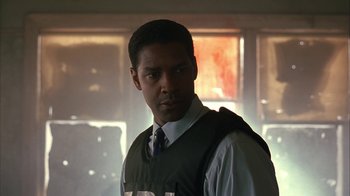 Movie still from “The Siege” (1998), directed by Edward Zwick – A man wearing a vest and tie in a dimly lit room; Close Up shot, Low angle