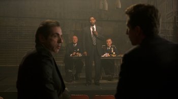 Movie still from “The Siege” (1998), directed by Edward Zwick – A group of men sitting around a room; Wide shot, Over the shoulder angle