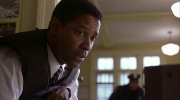 Movie still from “The Siege” (1998), directed by Edward Zwick – A man in a suit and tie looking at the camera; Close Up shot, Low angle