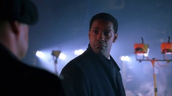 Movie still from “The Siege” (1998), directed by Edward Zwick – A man standing in the dark in front of lights; Close Up shot, Over the shoulder angle