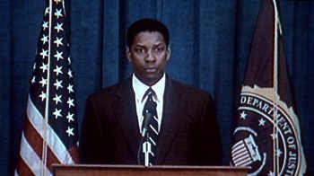 Movie still from “The Siege” (1998), directed by Edward Zwick – A man wearing a suit and tie standing in front of a podium; Close Up shot, Low angle