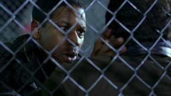 Movie still from “The Siege” (1998), directed by Edward Zwick – A person behind a chain link fence; Close Up shot, Over the shoulder angle