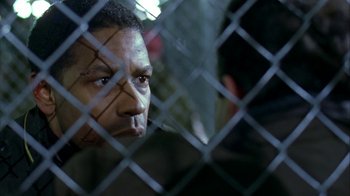 Movie still from “The Siege” (1998), directed by Edward Zwick – A person behind a chain link fence; Close Up shot, Over the shoulder angle