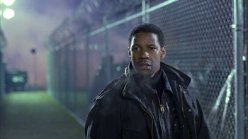 Movie still from “The Siege” (1998), directed by Edward Zwick – A man standing in front of a chain link fence at night; Medium shot, Low angle