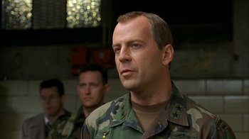 Movie still from “The Siege” (1998), directed by Edward Zwick – A man in military fatigues standing in front of two other men; Close Up shot, Low angle