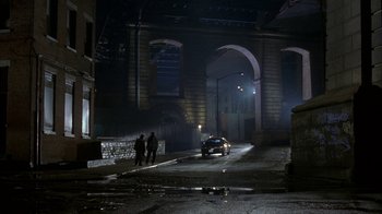 Movie still from “The Siege” (1998), directed by Edward Zwick – A car parked on the side of the road at night; Extreme Wide shot, High angle