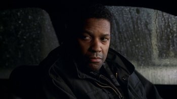 Movie still from “The Siege” (1998), directed by Edward Zwick – A man in a black jacket sitting in front of a tree; Close Up shot, Over the shoulder angle