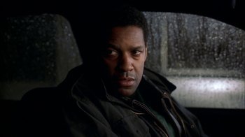 Movie still from “The Siege” (1998), directed by Edward Zwick – A man sitting in the back seat of a car; Close Up shot, Over the shoulder angle