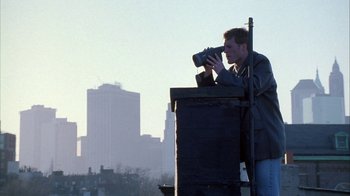Movie still from “The Siege” (1998), directed by Edward Zwick – A man taking a picture of a city skyline; Wide shot, Low angle