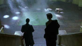 Movie still from “The Siege” (1998), directed by Edward Zwick – Two people are walking up stairs towards a pool of water; Extreme Wide shot, High angle